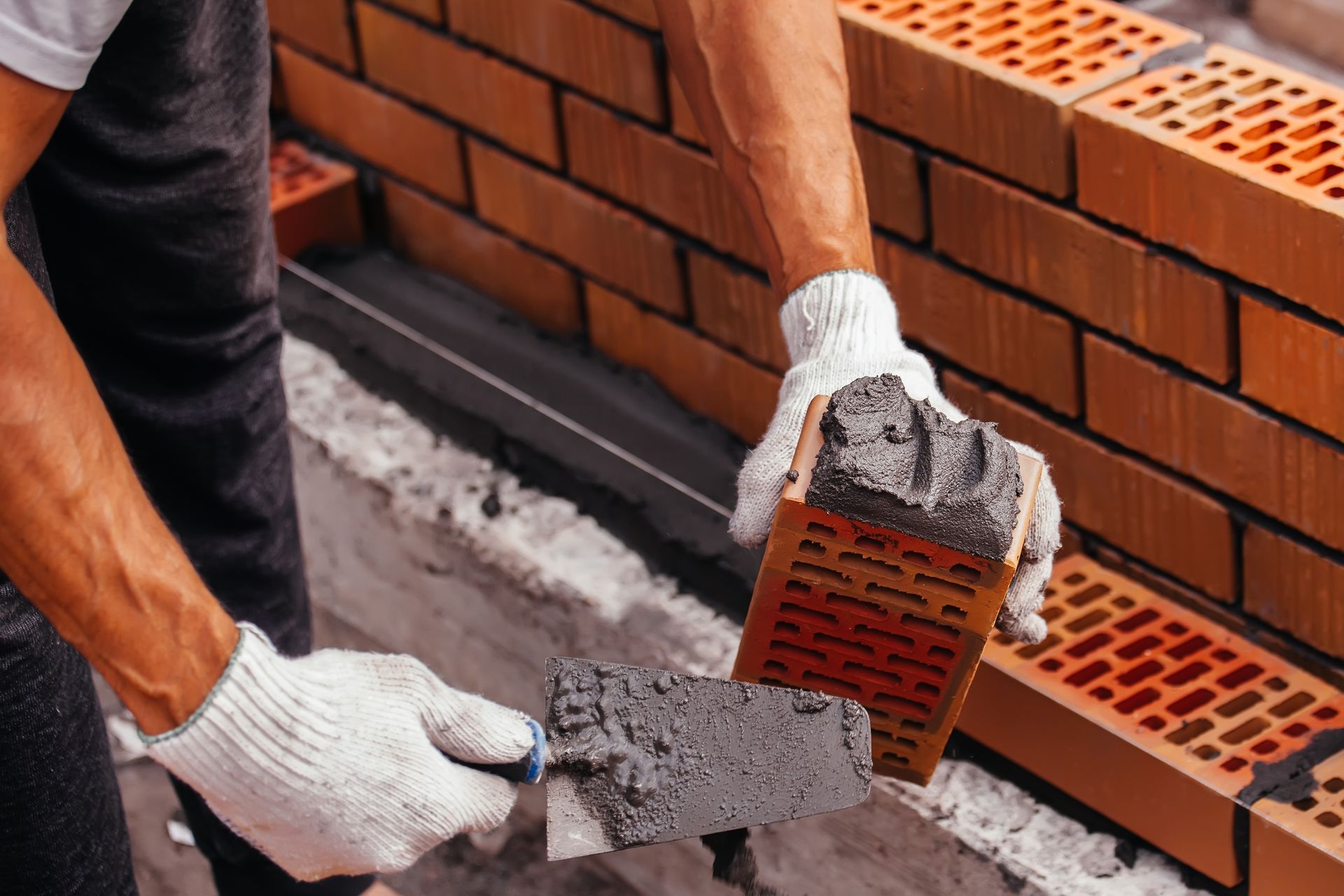 A man is laying bricks on a wall with a trowel.