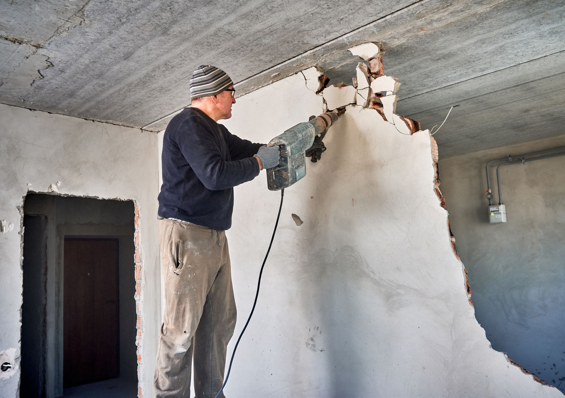 A man is working on a wall with a hammer.