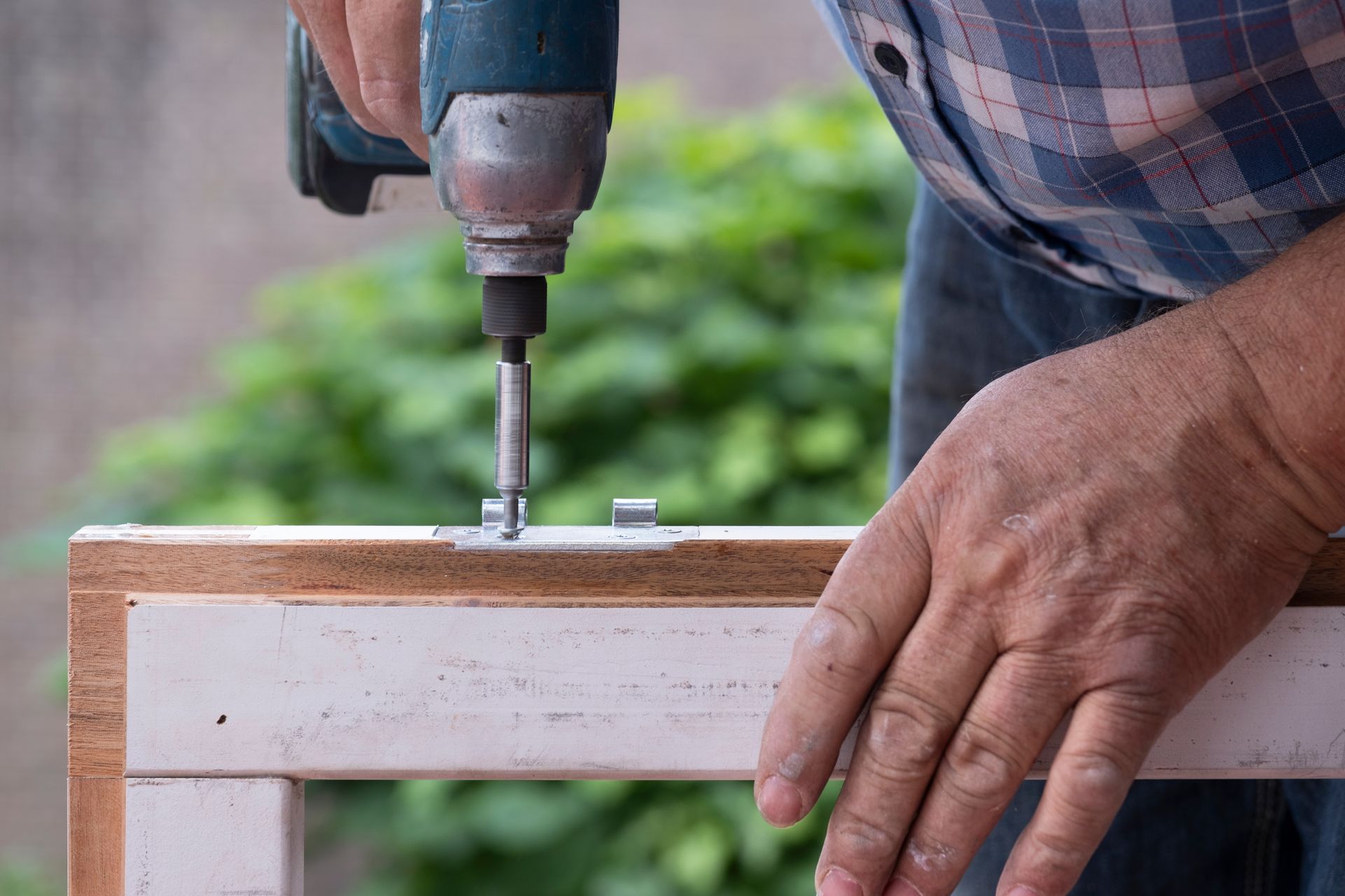 A man is using a drill to drill a hole in a piece of wood.
