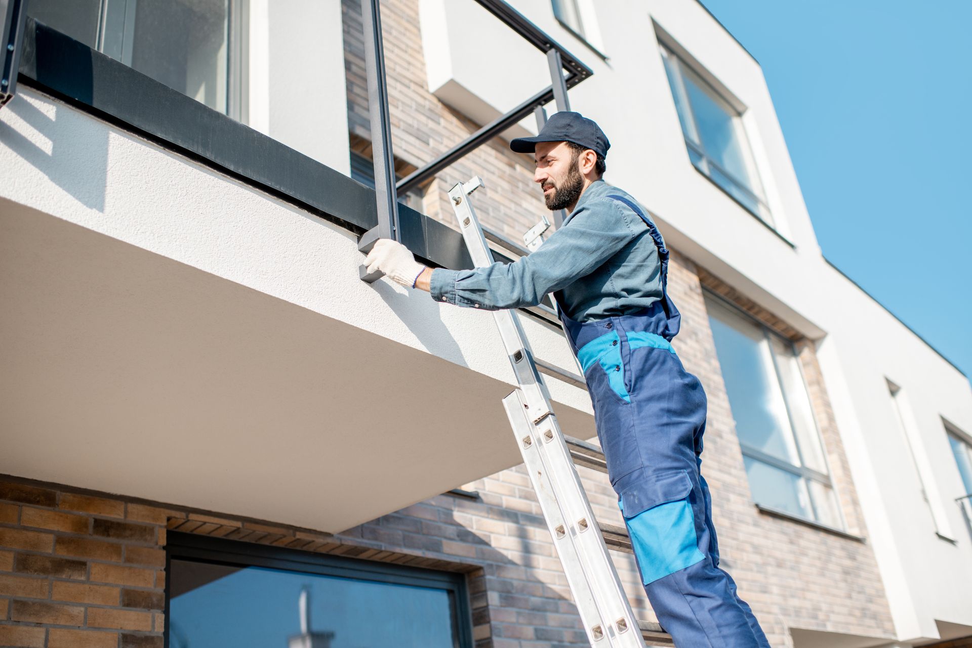 A man is standing on a ladder outside of a building.
