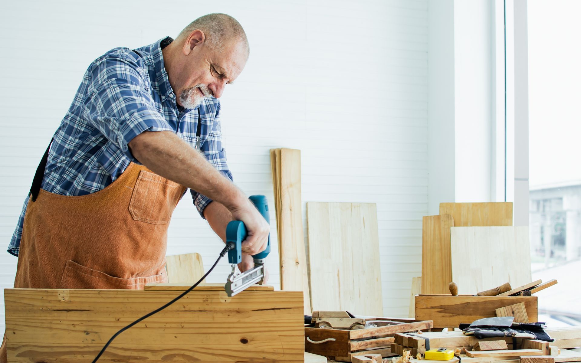 A man is using a drill to cut a piece of wood.