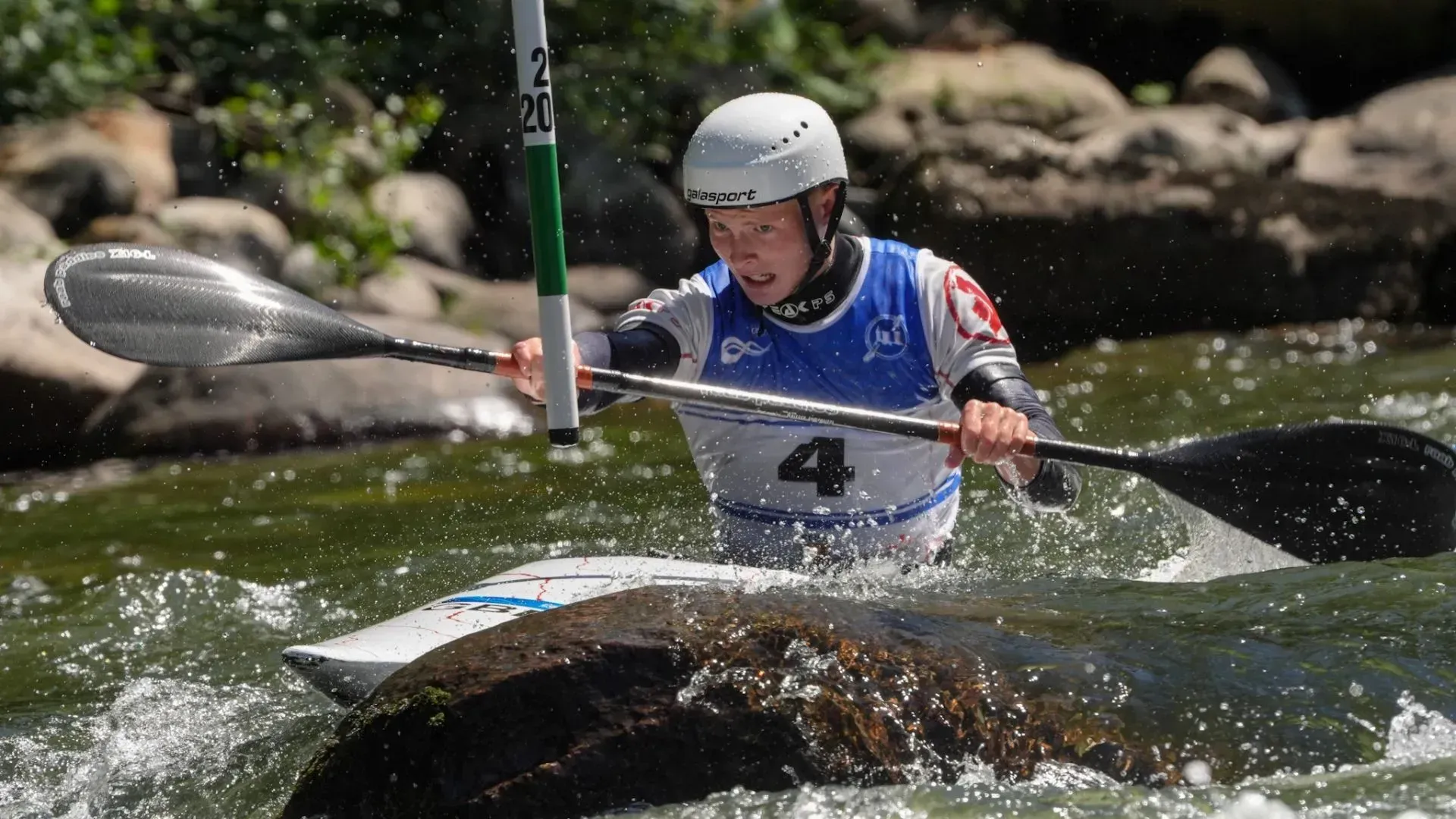 A man is paddling a kayak through a river.