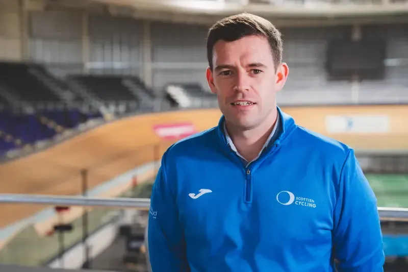 A man in a blue jacket is standing in front of a bicycle track.