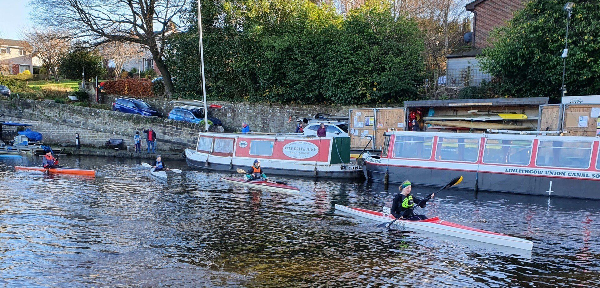 A group of people are rowing kayaks down a river.