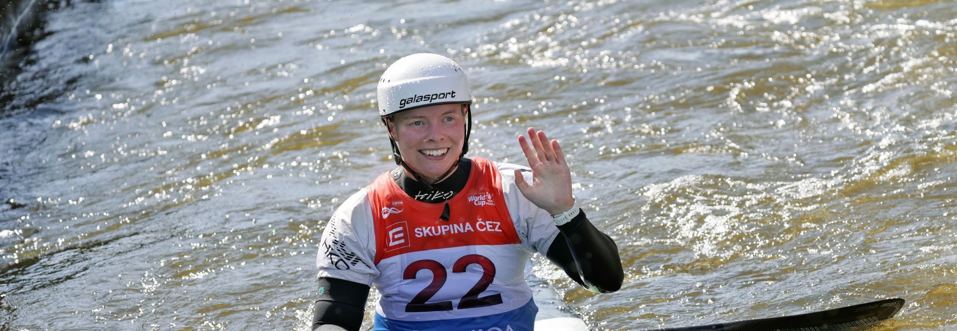 A person wearing a helmet and a shirt with the number 22 on it is standing in the water.