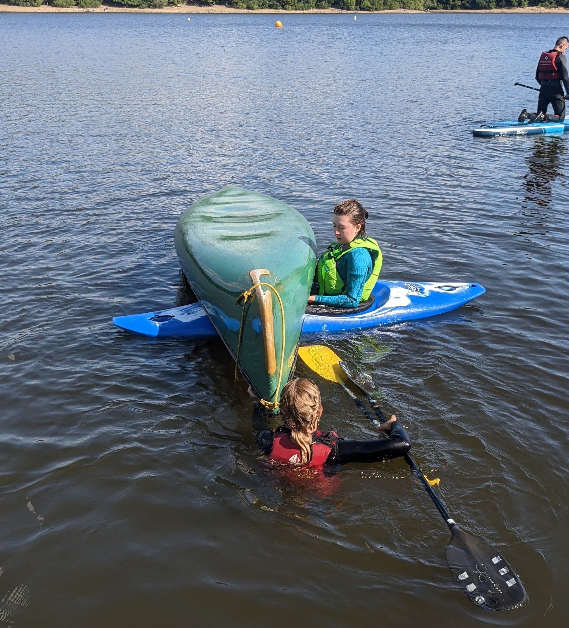 A group of people are paddling kayaks on a lake.