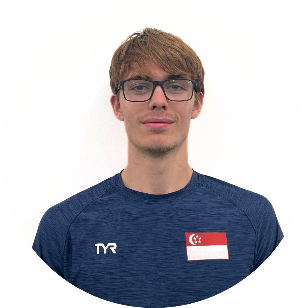 A young man wearing glasses and a blue shirt with the Singapore flag, smiling.