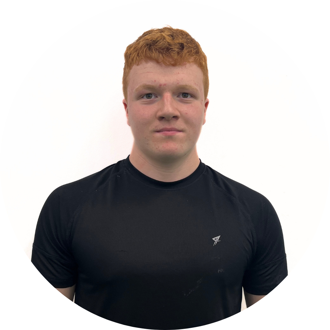 Young man with red hair in a black shirt, smiling slightly, against a white background.