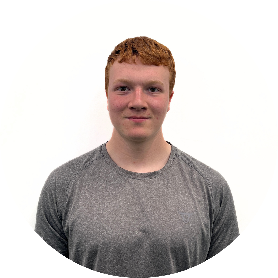 Young man with red hair wearing a gray shirt, smiling at the camera against a white background.