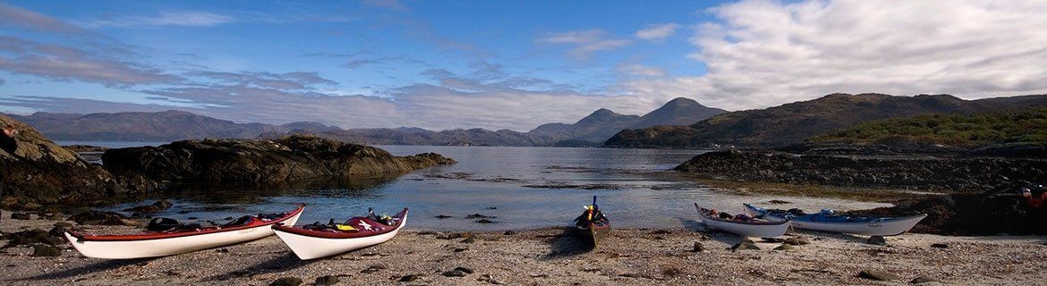 Two boats are sitting on the shore of a lake.