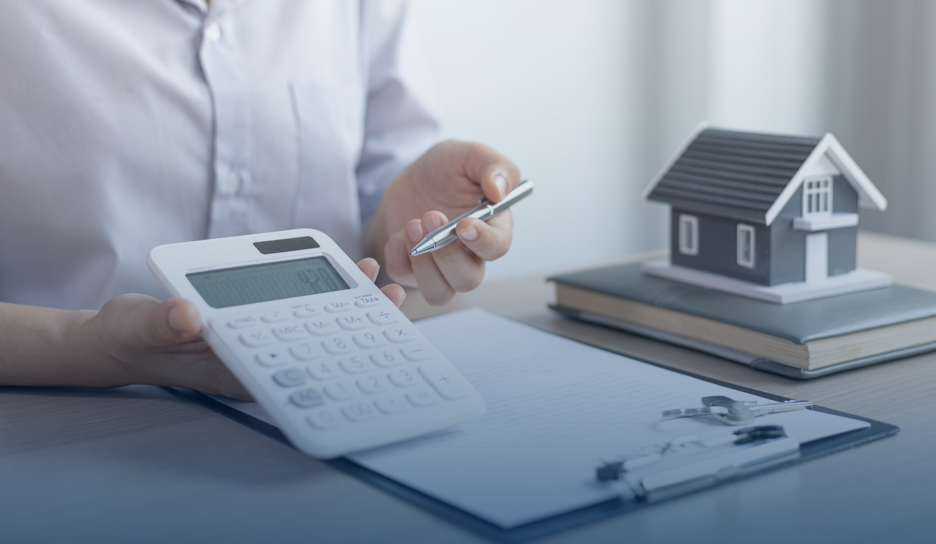 Une personne utilise une calculatrice pour calculer le coût d'une maison.