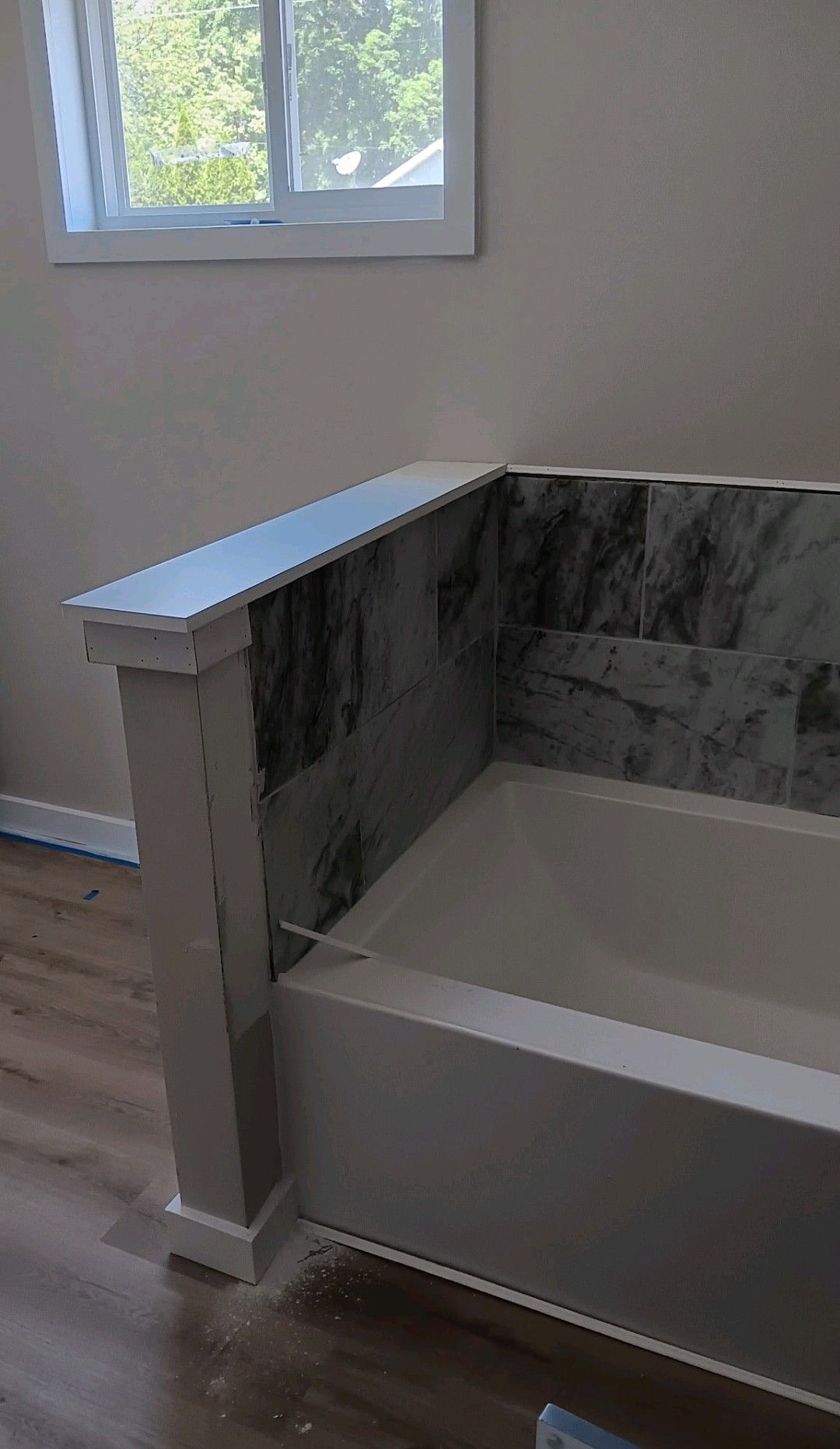 Marble-accented bathtub with a white bench beside a window in a bathroom