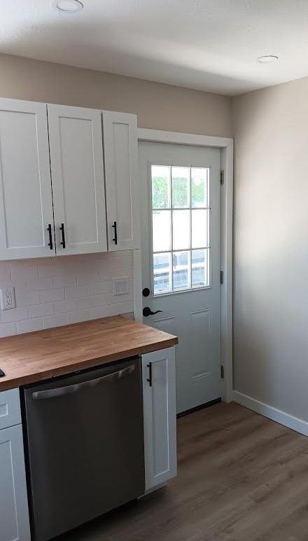Small modern kitchen with white cabinets, wood countertop, and a back door with window panes.