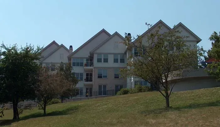 A Large House Sits on Top of A Grassy Hill with Trees in Front of It | Sheboygan, WI | Elite Builds