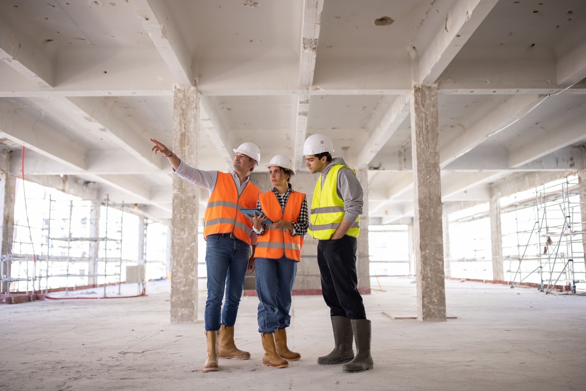 Three workers discussing and looking at a digital tablet as they visiting a building site.