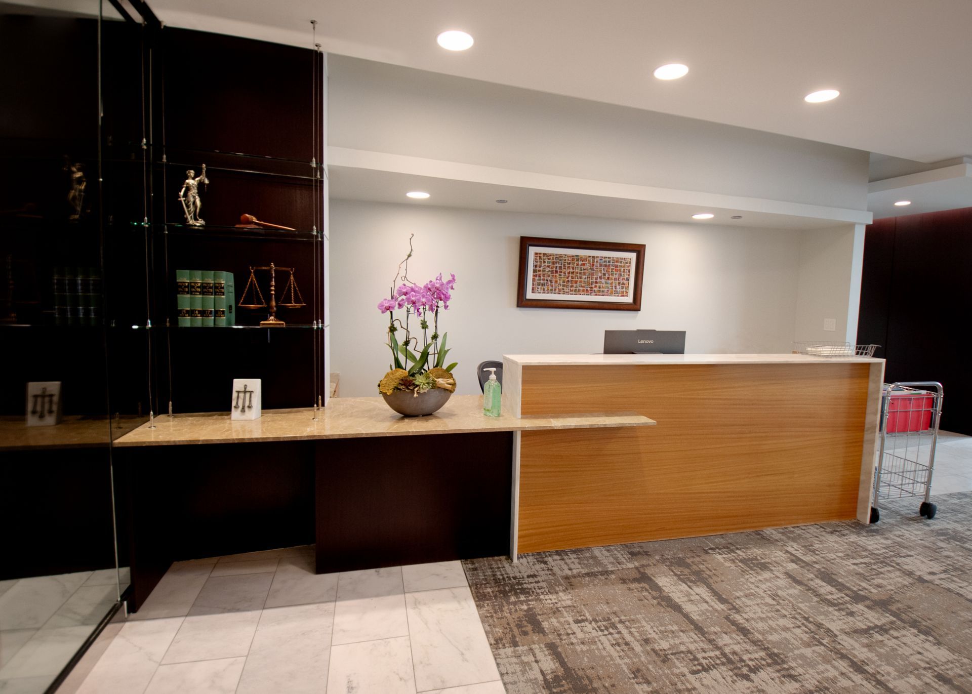 Law office reception area with a wooden desk, artwork, and a display case with legal symbols.