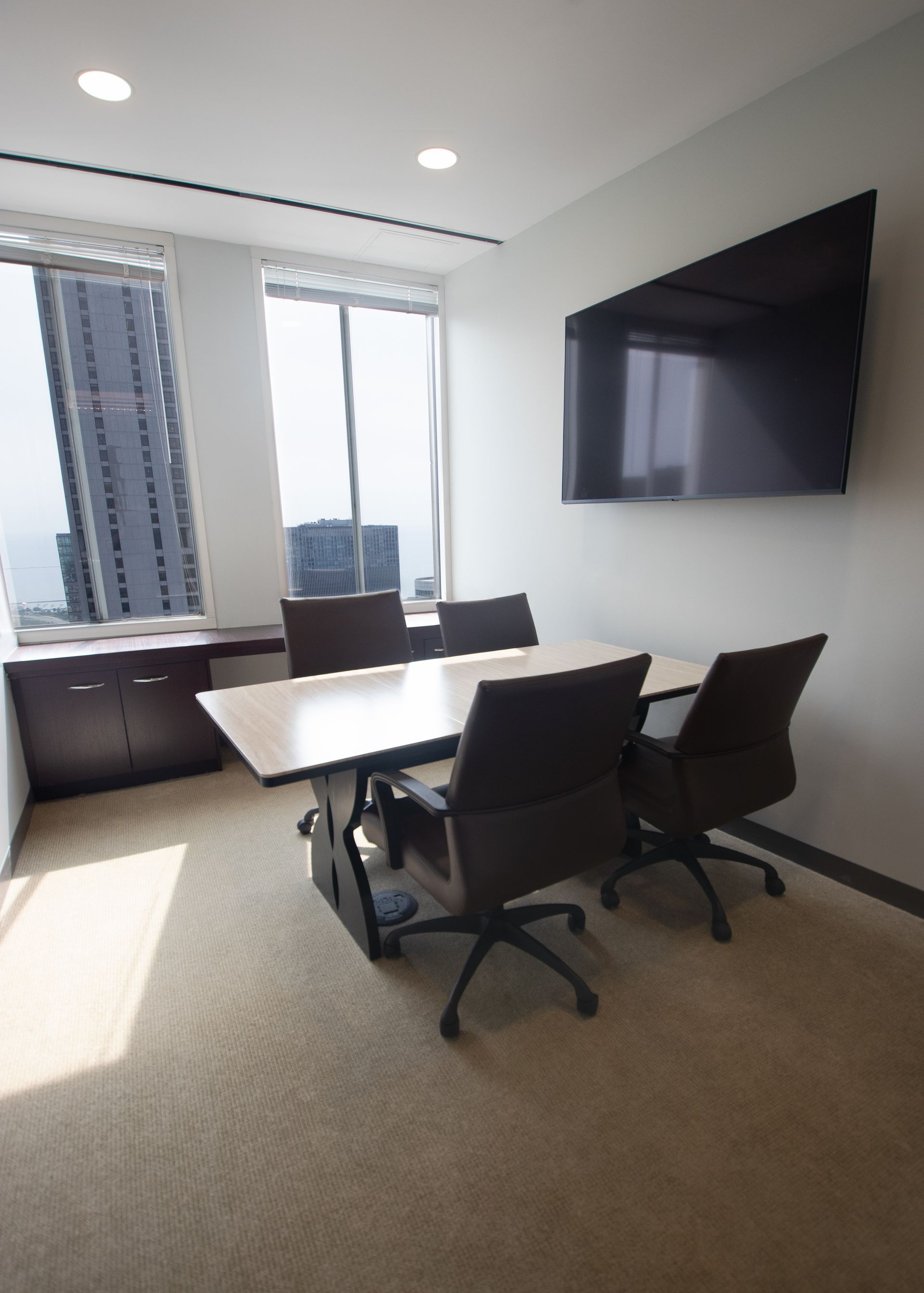 Conference room with table, chairs, TV, window, and cabinet.