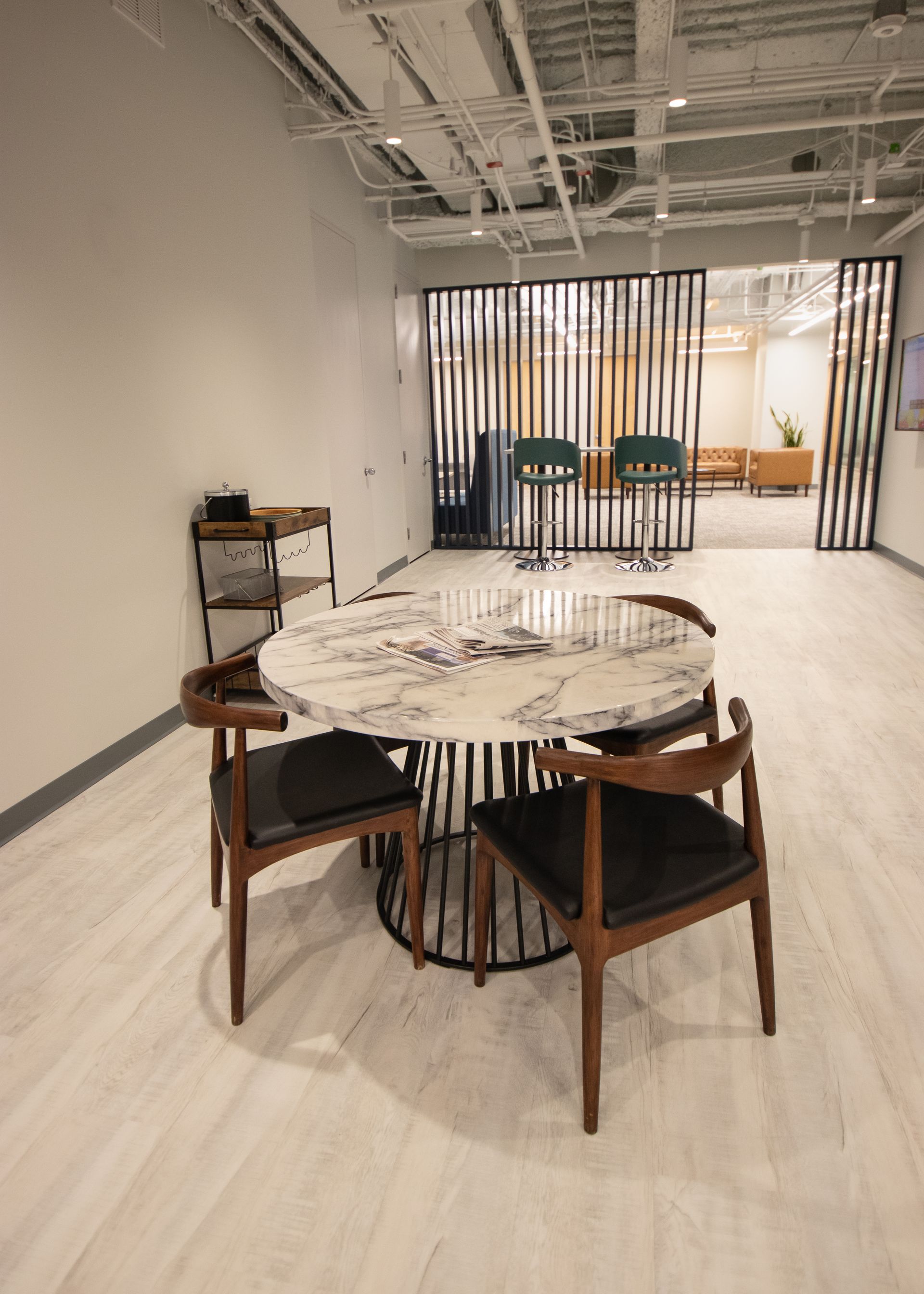 Round marble table with wooden chairs in a bright office space. Black and gold room dividers.