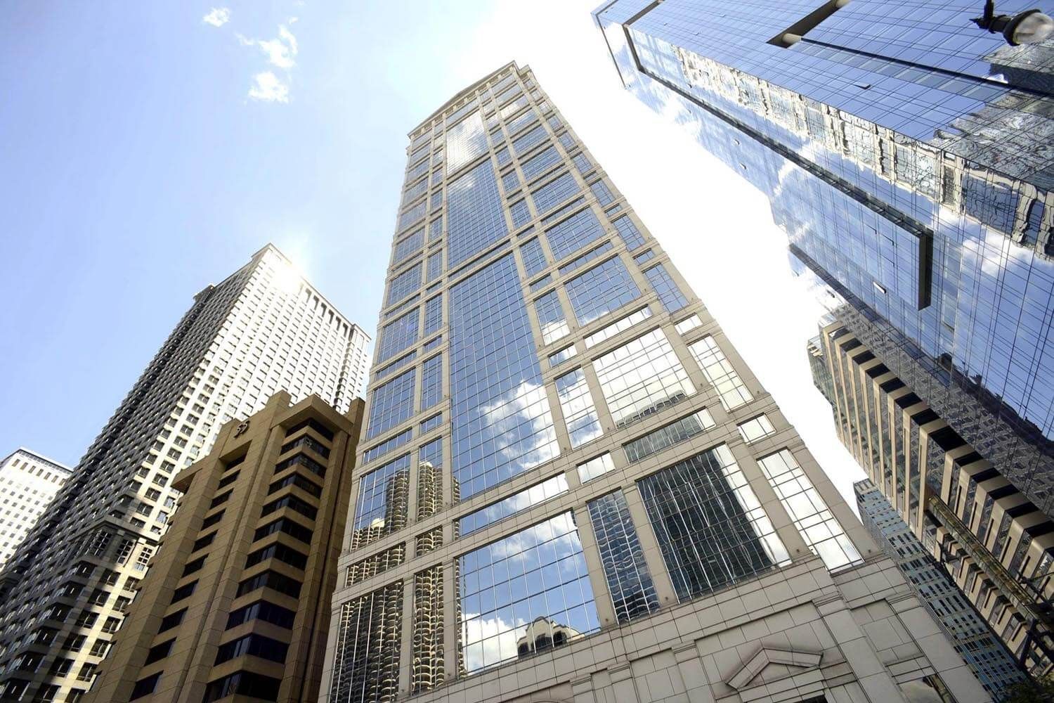 Skyscrapers reaching toward the sky, reflecting blue sky and sunshine.