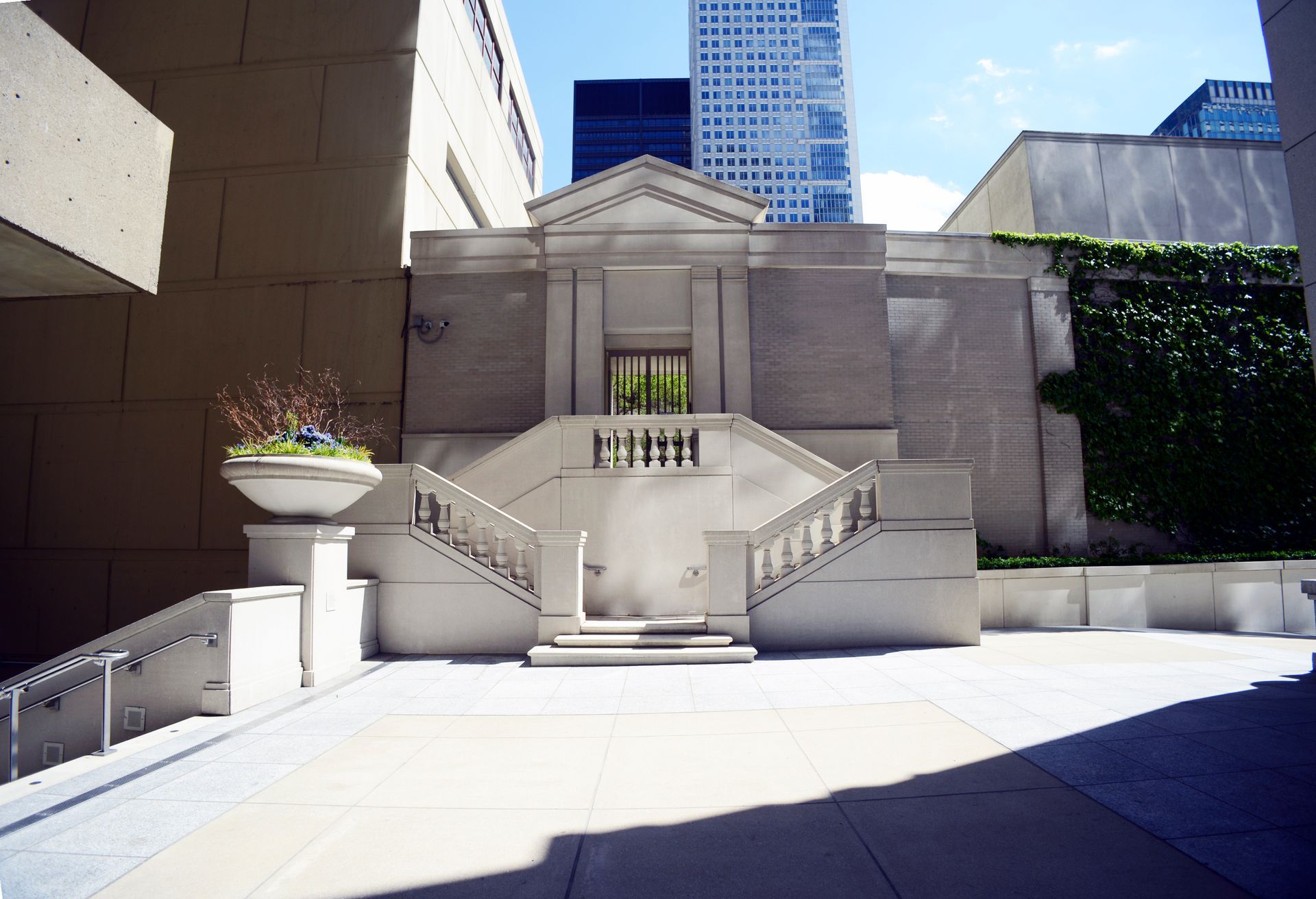 Stone building with stairs, surrounded by other buildings, blue sky.