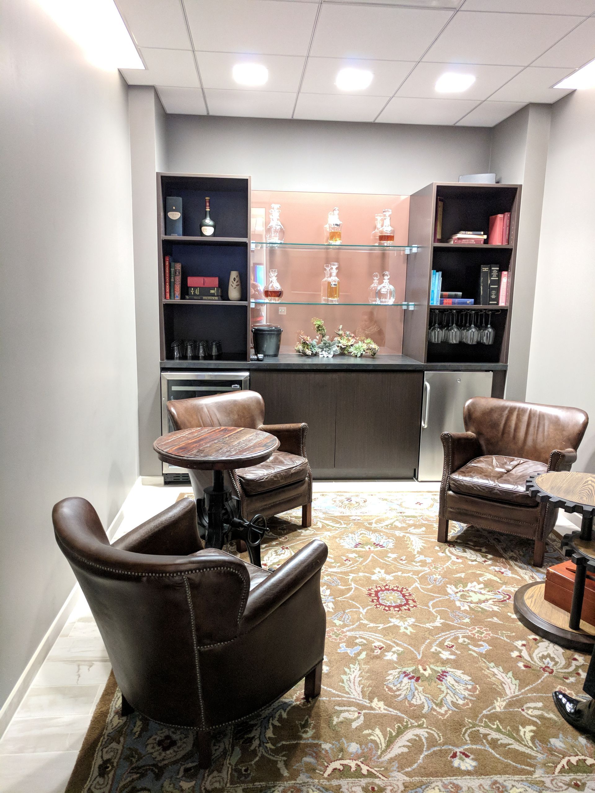 Cozy bar area with leather chairs, rug, and liquor cabinet.