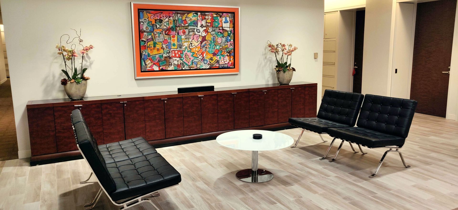 Reception area with a modern design featuring art, black leather chairs, and a round table.