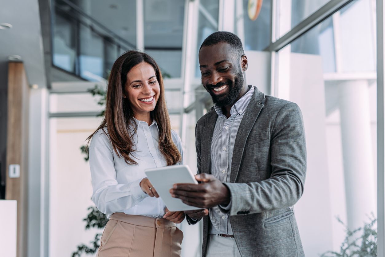 Woman and man looking at a tablet, smiling, in an office setting.