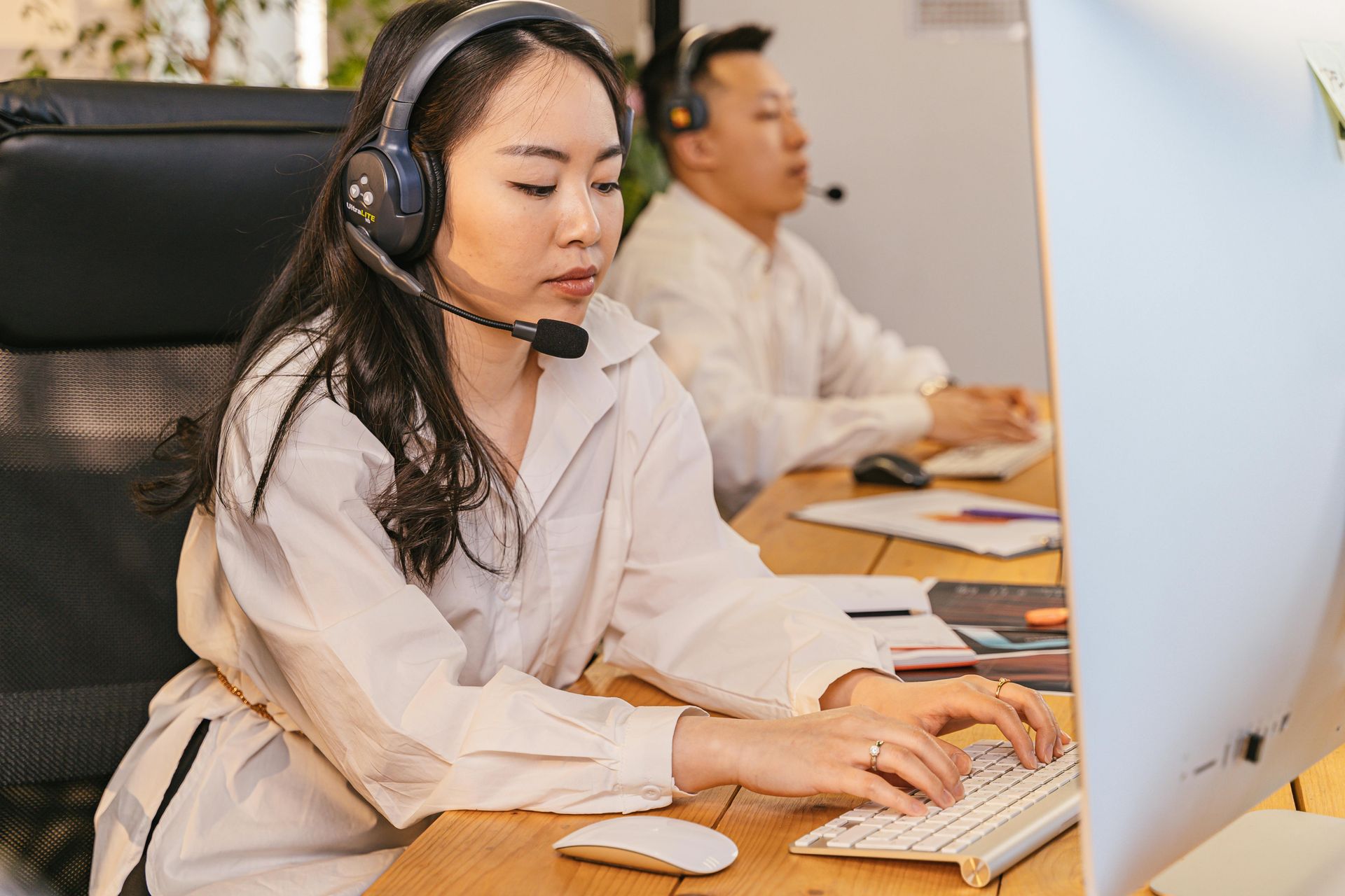 Woman and man in headsets working at computers in office.