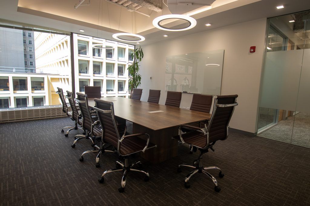 Conference room with large wooden table, brown leather chairs, and large windows.