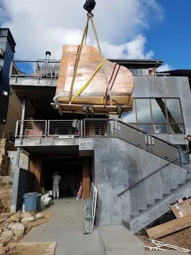 A piano is being lifted into a house by a crane.