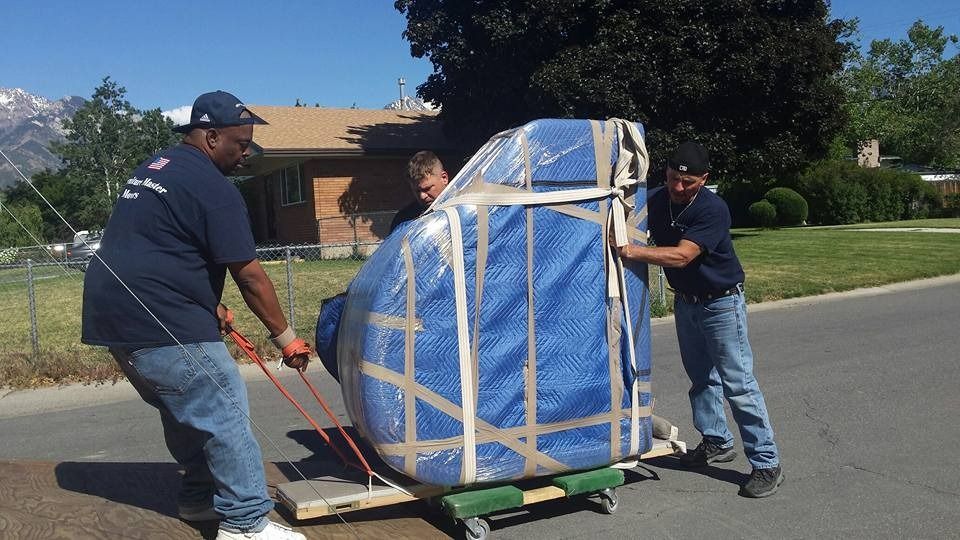 A group of men are moving a piano on a dolly.