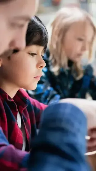 A group of children are sitting at a table in a classroom.