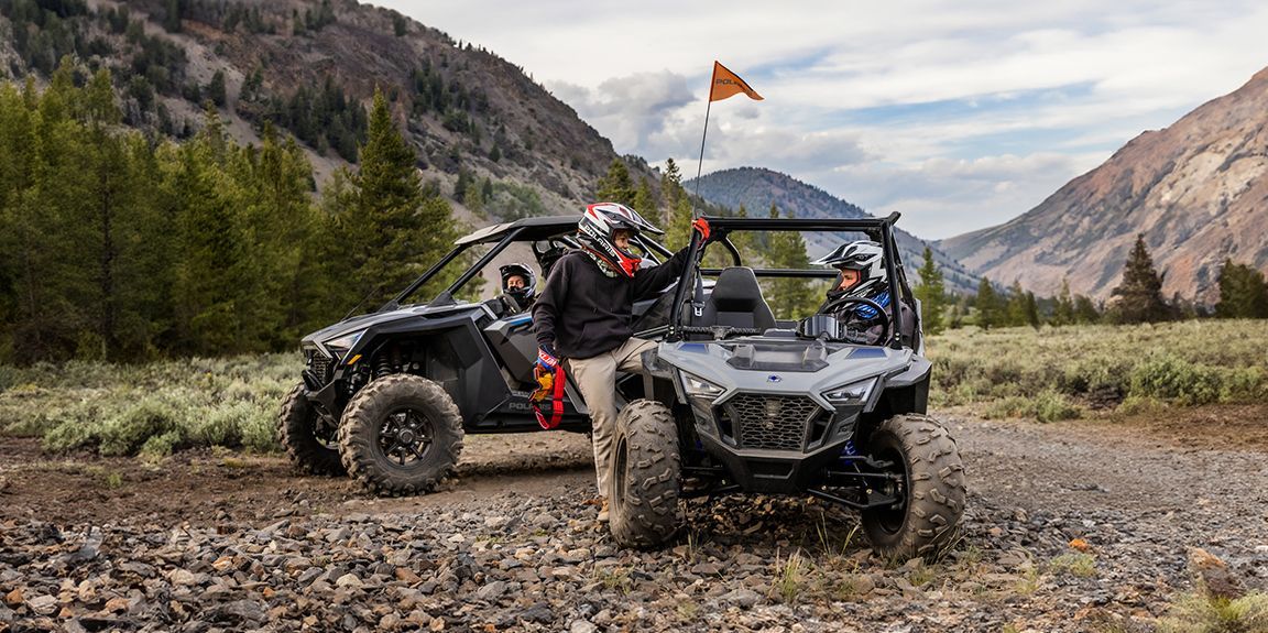 Two atvs are parked next to each other on a dirt road.