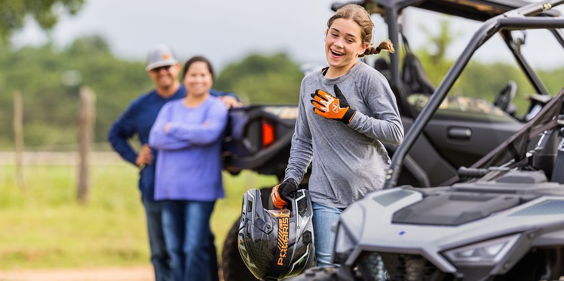 an image of a girl holding a helmet near a utv