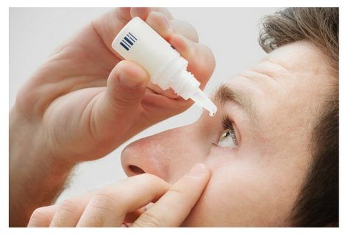man putting in eye drops to treat itchy eyelids