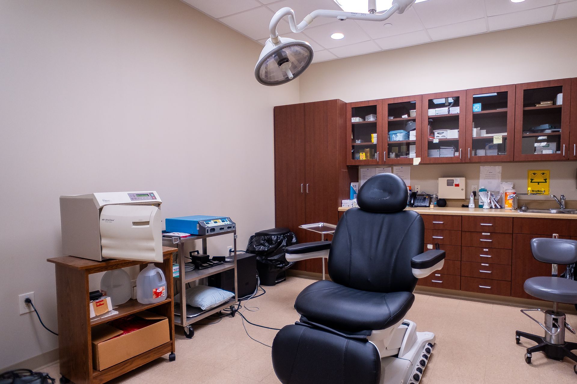 An operating room with a black chair and a surgical light