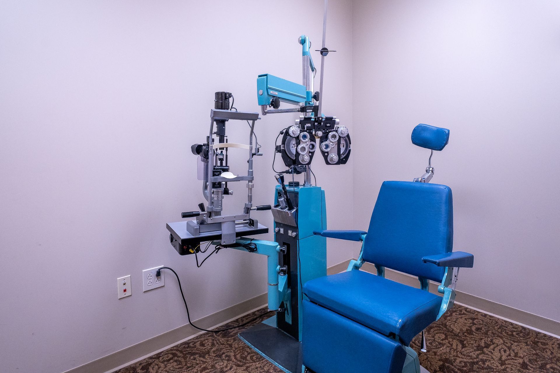 An ophthalmologist 's office with a blue chair and a machine.