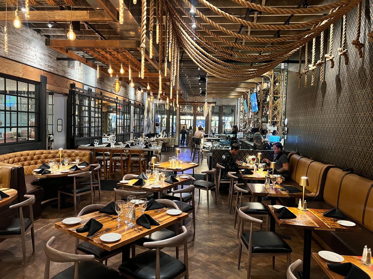 A restaurant filled with tables and chairs and a rope hanging from the ceiling.