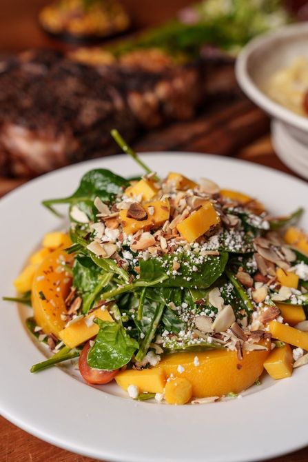 A close up of a salad on a white plate on a table.