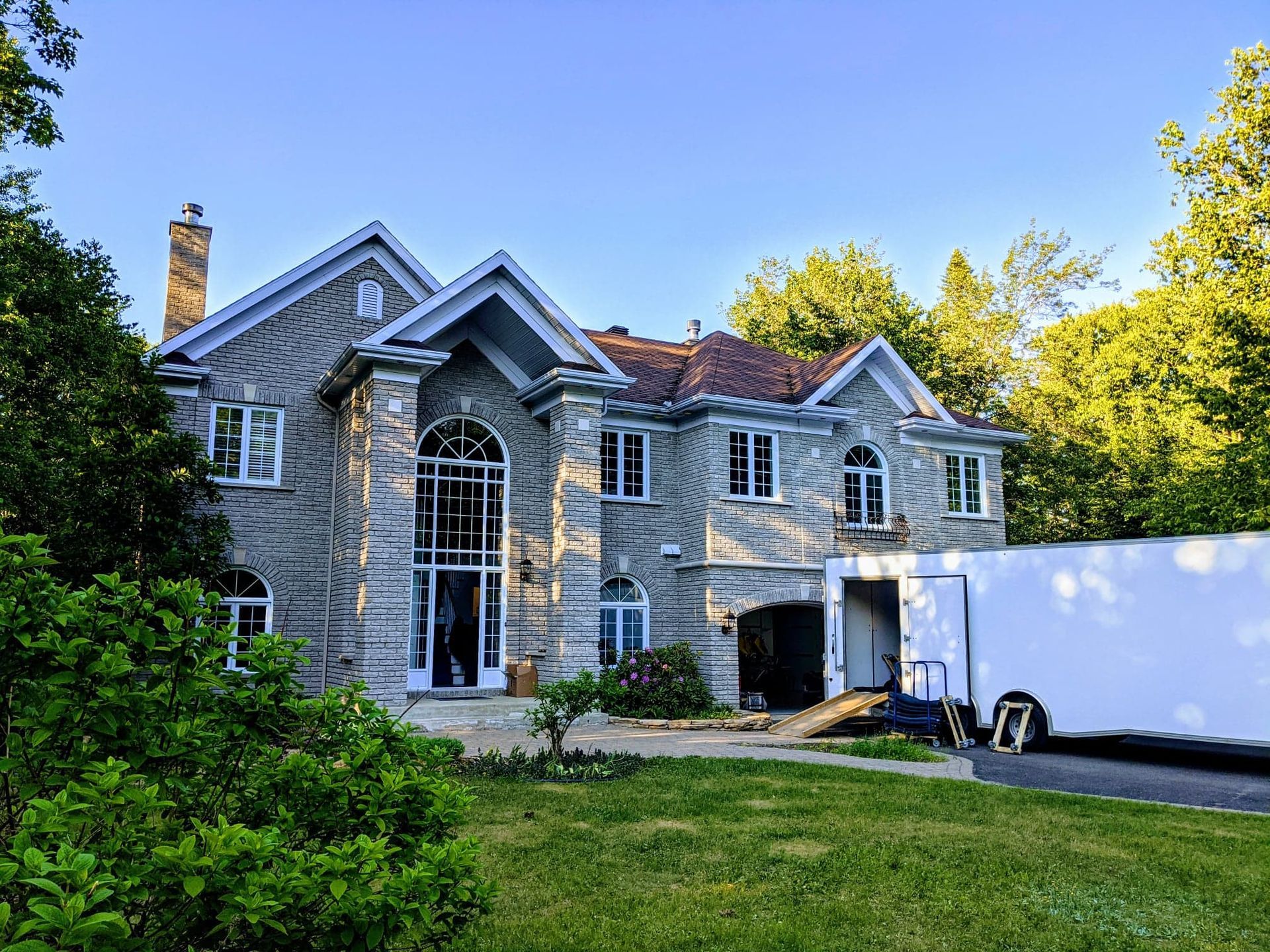 Une grande maison avec un camion blanc garé devant