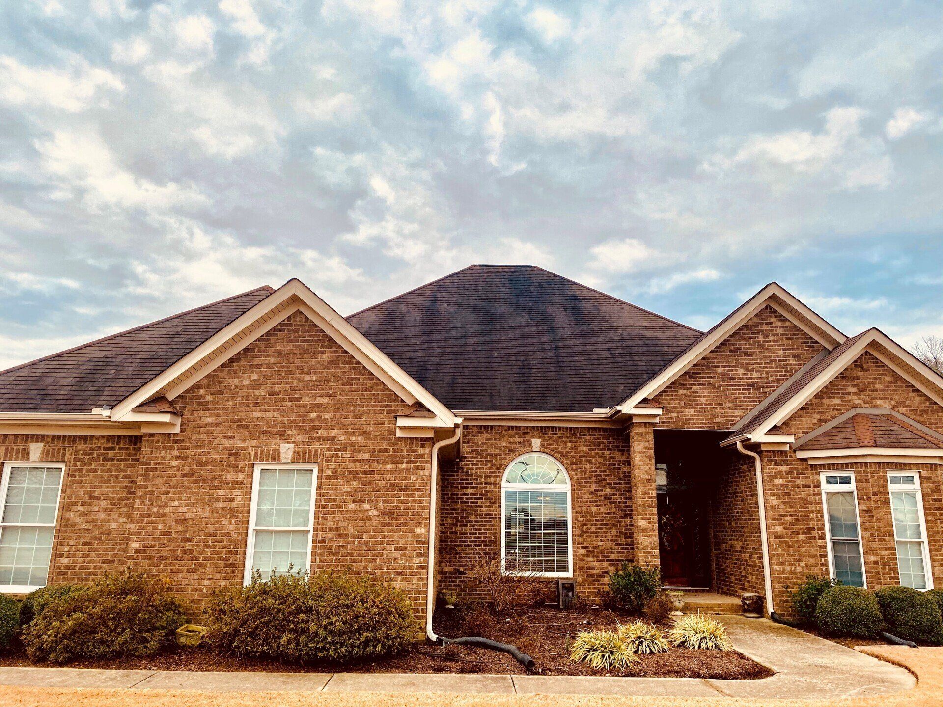 A large brick house with a black roof and white trim