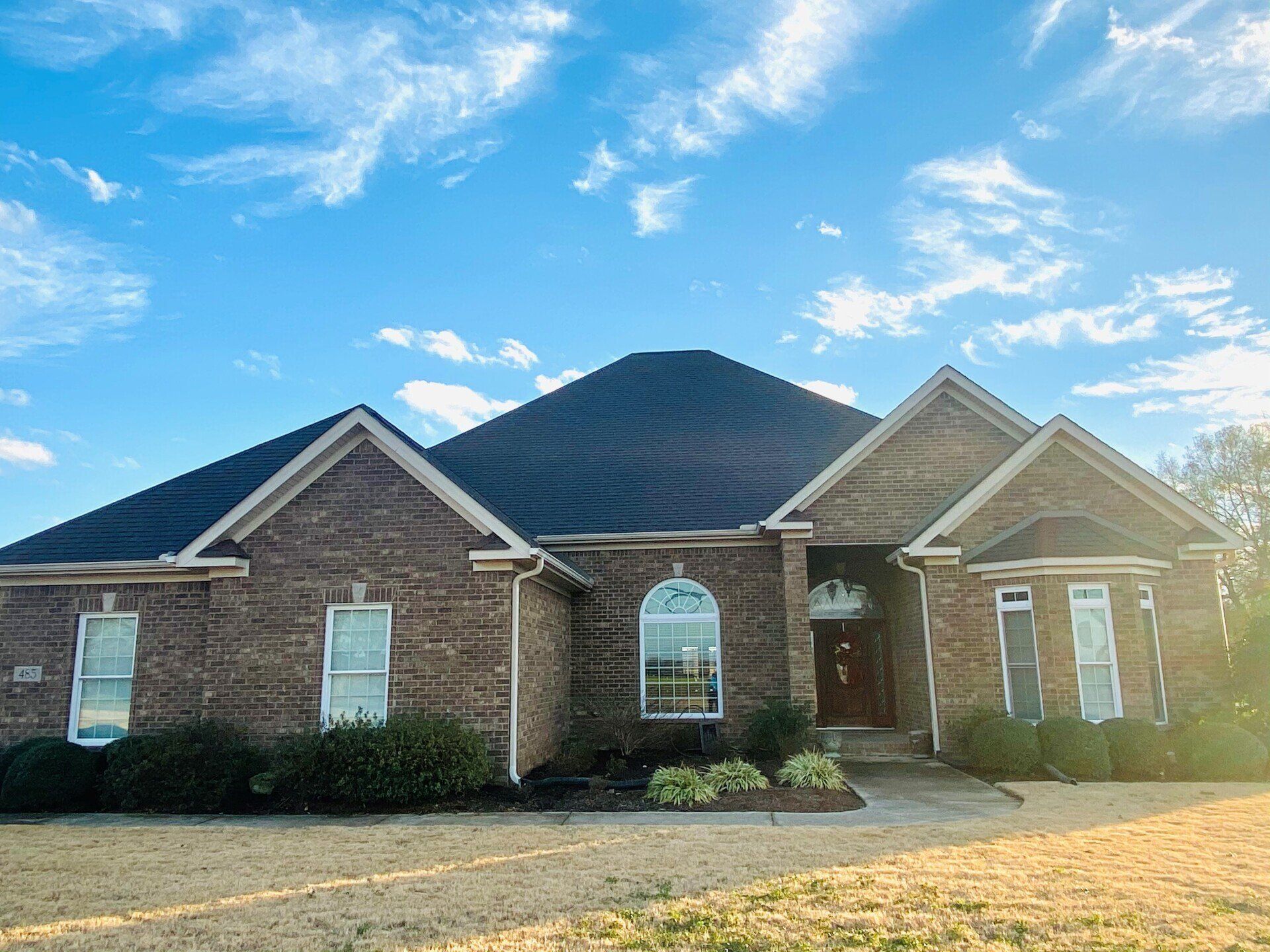 A large brick house with a blue sky in the background.