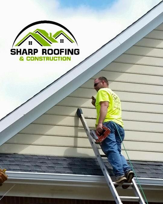 A man on a ladder working on a roof for sharp roofing & construction