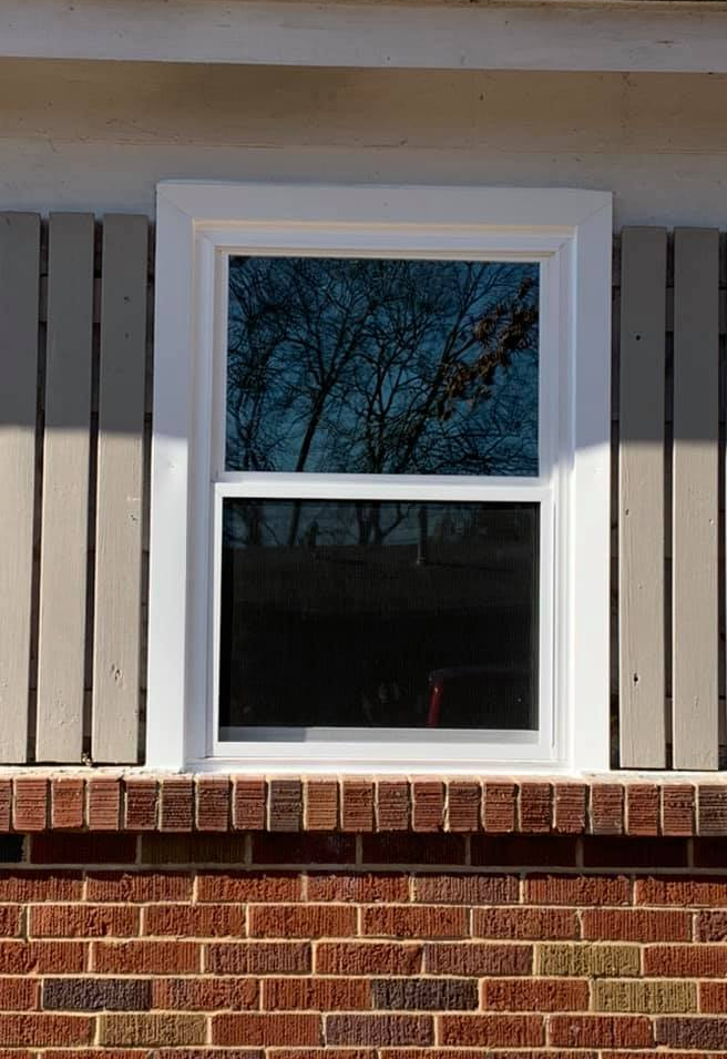 A window on the side of a brick house with a white frame.