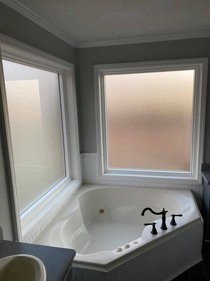A bathroom with a jacuzzi tub and two windows.