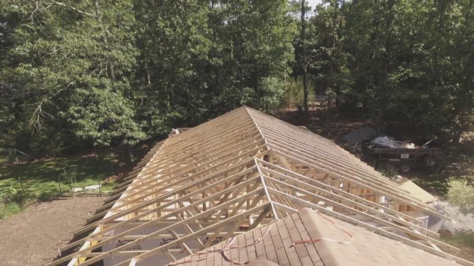 An aerial view of a roof under construction with trees in the background.