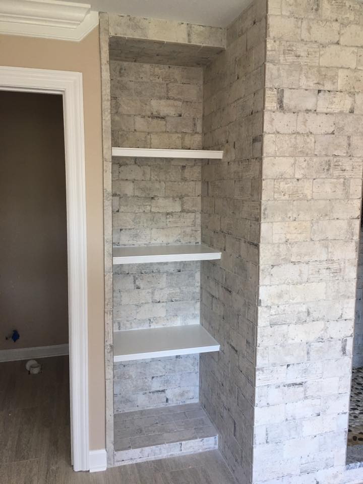 A room with a brick wall and shelves in it.