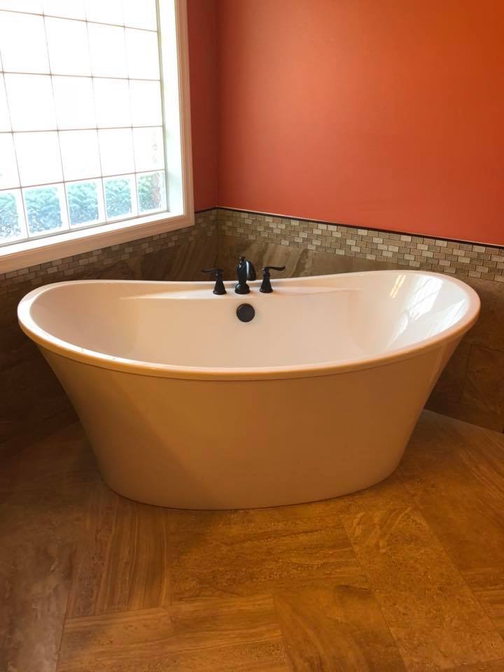A white bathtub is sitting in a bathroom next to a window.