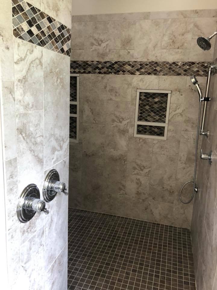 A walk in shower with tiled walls and a shower head.