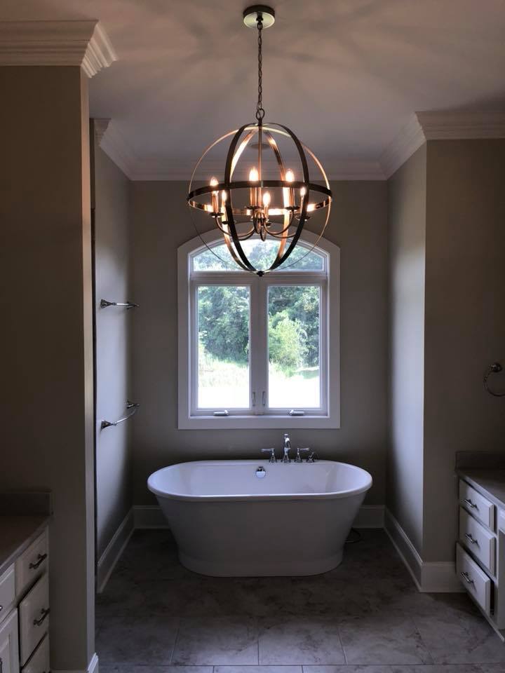 A bathroom with a bathtub and a chandelier hanging from the ceiling.